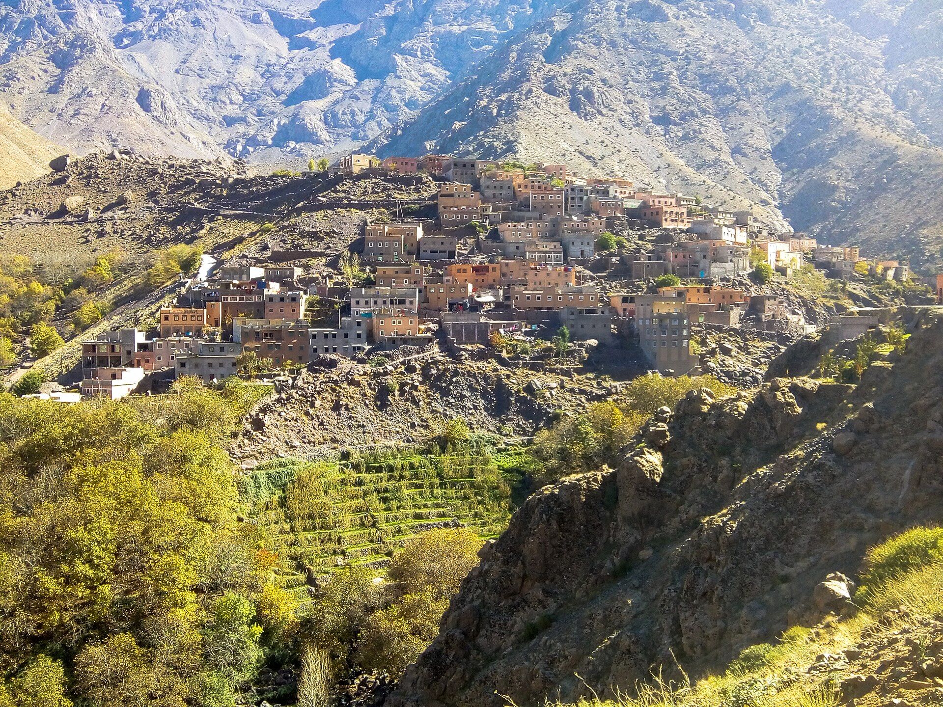 A Berber village of mud-brick houses on a slope, with the snow-capped peaks of the High Atlas behind it