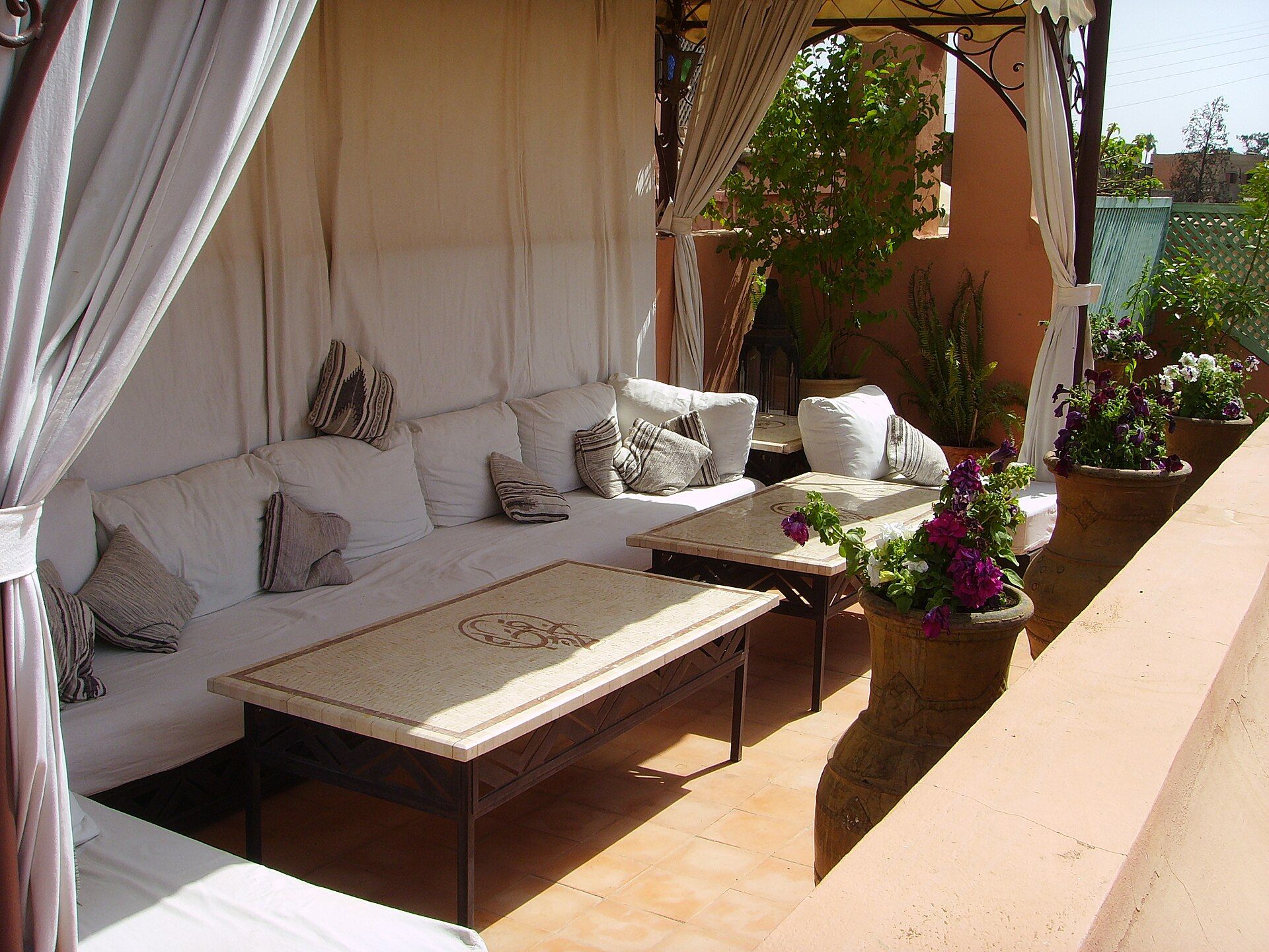 Roof terrace of a riad in Marrakesh with white cushions and flowers