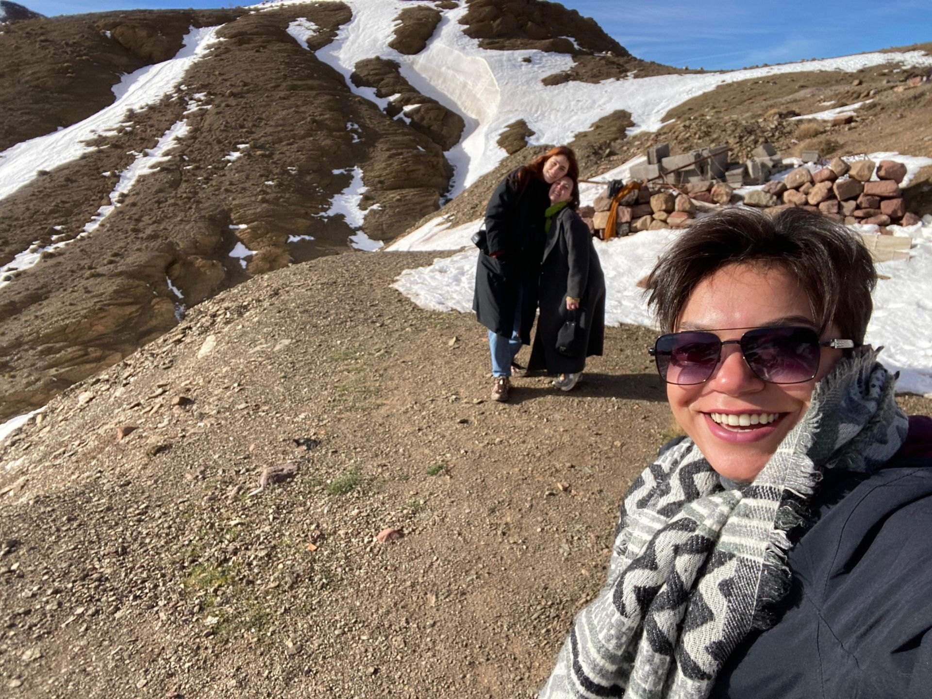 Soukayna (right, in sunglasses) takes a selfie in the snowy Atlas Mountains, with two travelers in the background