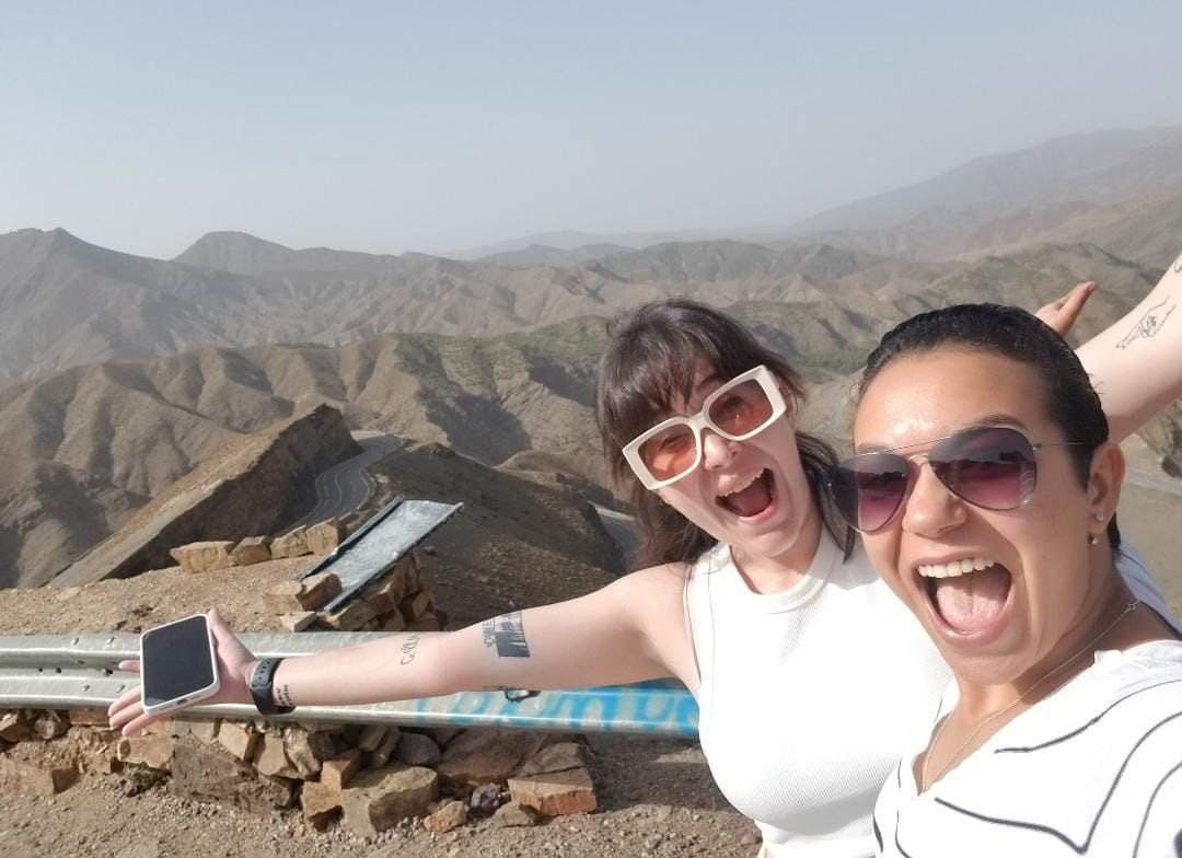 Soukayna (right, in sunglasses) cheers with a traveler on a mountain pass in the Atlas
